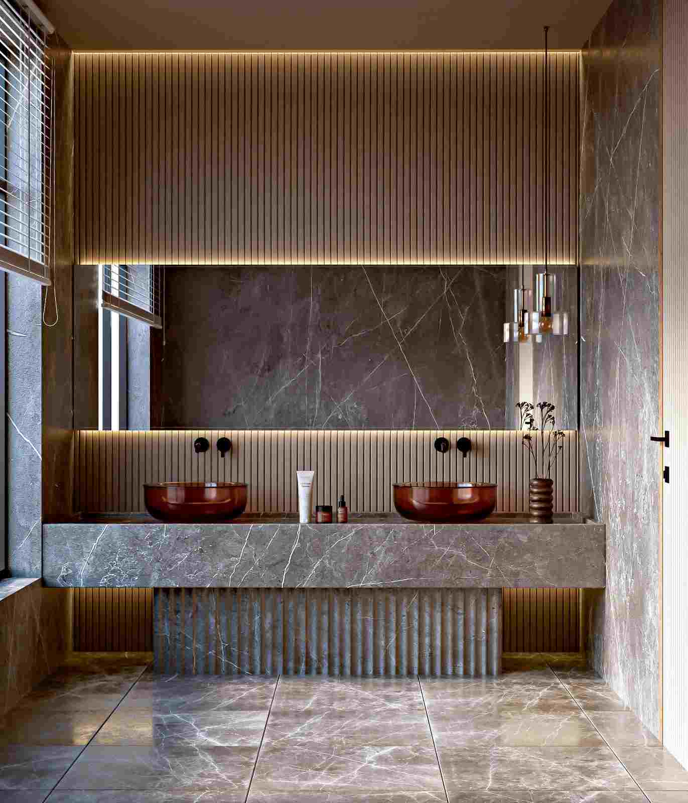 Baño con dos lavabos sobre encimera veteada, espejo rectangular grande, iluminación indirecta y lámparas colgantes.
