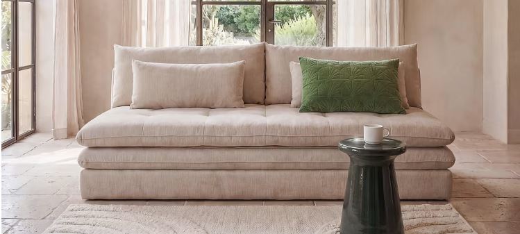 Sofá cama de Maisons du Monde Clio con cojines y mesa ausiliar