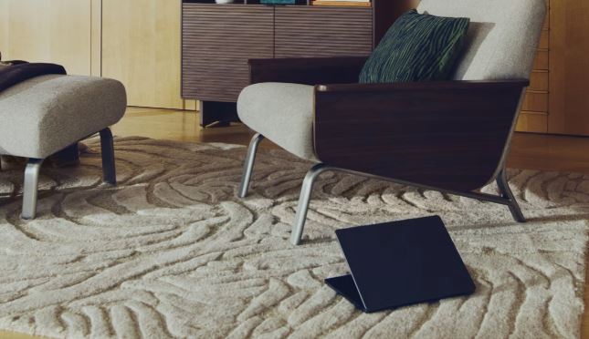 Alfombra beige con dibujo de cebra en relieve junto a una butaca clara con estructura de madera oscura