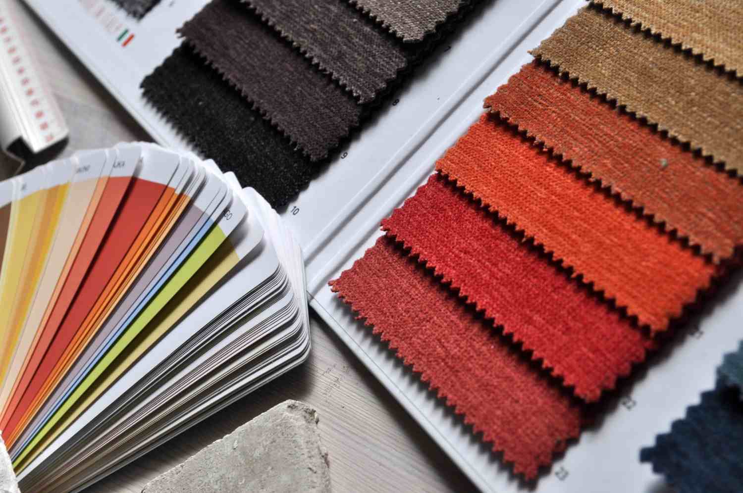 Muestrario de telas en tonos grises, beige y rojizos junto a una carta de colores